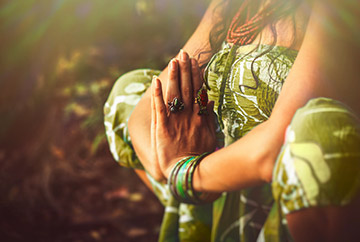 Frau in grünem Kleid und indischem Schmuck praktiziert Yoga