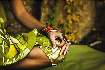 indische Frau mit grün gemustertem Kleid praktiziert Yoga